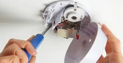 Certified technician wiring smoke detector during installation in Flagstaff, AZ